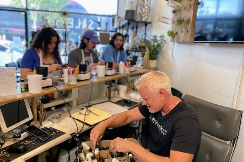 A person working at a counter with a computer and various items on it. 4