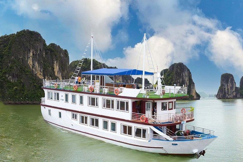 A large white boat with a blue roof and a red railing, floating on calm water with a mountainous landscape in the background. 3