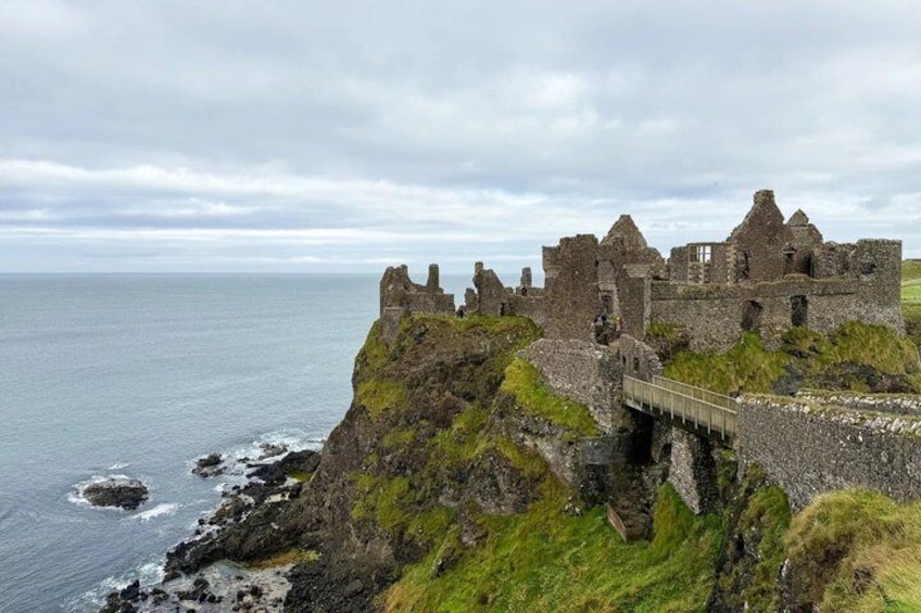 A coastal castle ruins with a bridge leading to it, surrounded by cliffs and the sea. 3