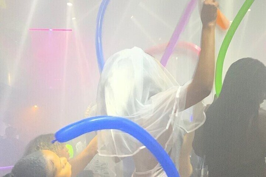 A person in a white dress with a raised arm, possibly dancing, surrounded by colorful streamers. 2