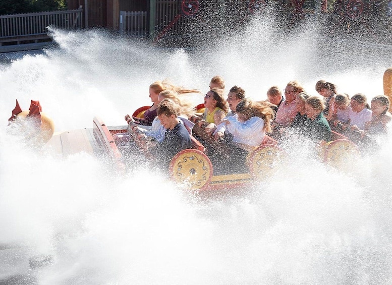 A group of people in a wooden boat being sprayed with water. 2