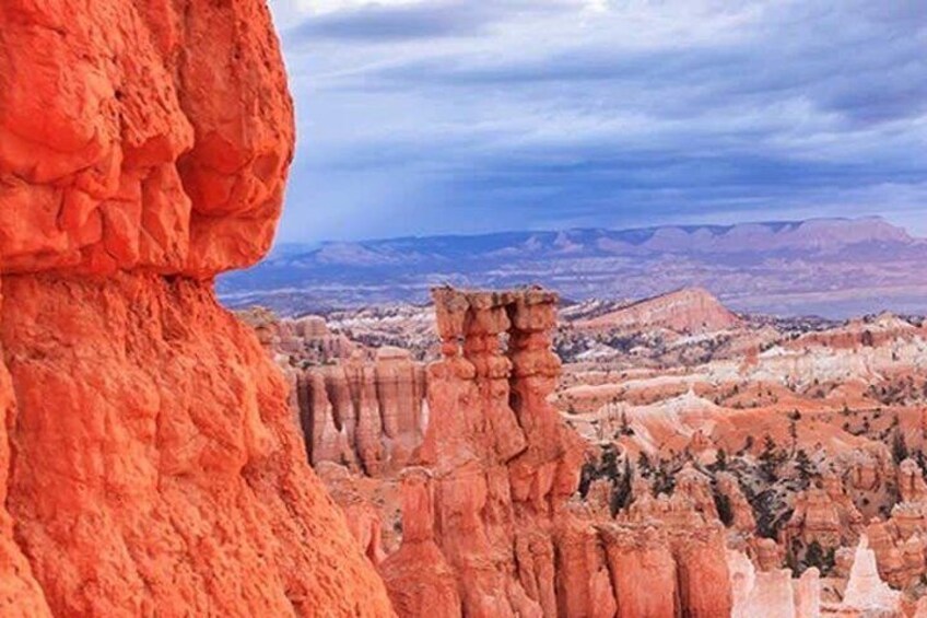A red rock formation with a view of a valley and distant mountains. 4