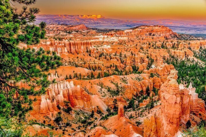 A canyon landscape with red rock formations, greenery, and a distant mountain range. 5