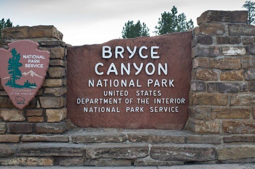 A Bryce Canyon National Park sign with a stone wall and a Department of the Interior emblem. 1