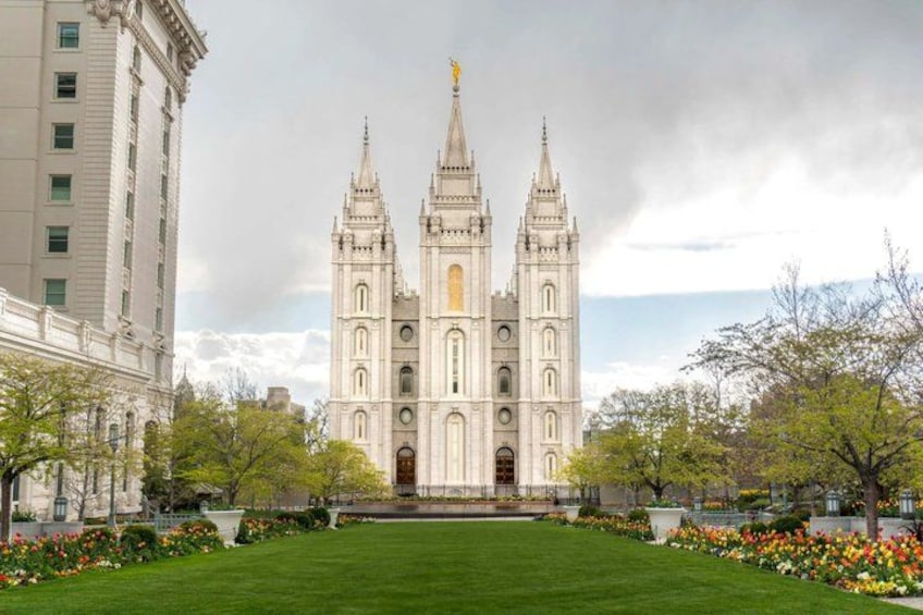 A large, ornate cathedral with two towers, surrounded by a well-maintained lawn and flowering trees. 1