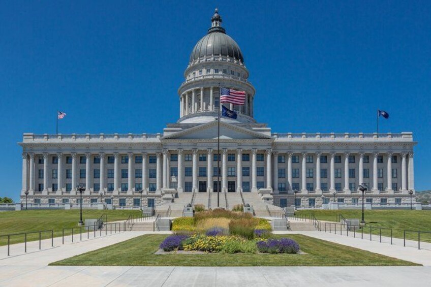 A large government building with a dome, flagpoles, and a well-maintained lawn. 1