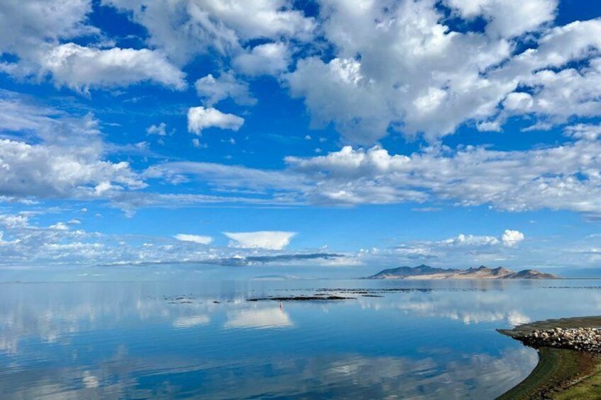 A calm lake with a clear reflection of the sky and mountains in the distance. 4