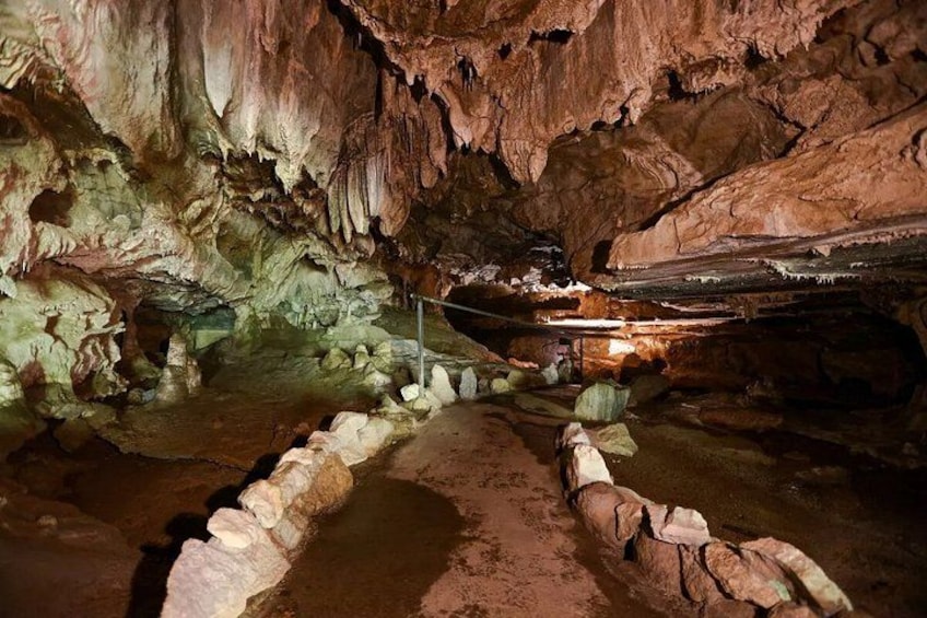 A cave with stalactites, a rope barrier, and a metal railing. 4