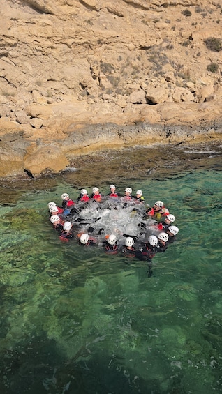 A group of people in helmets and life jackets floating in a circular raft on a river. 3