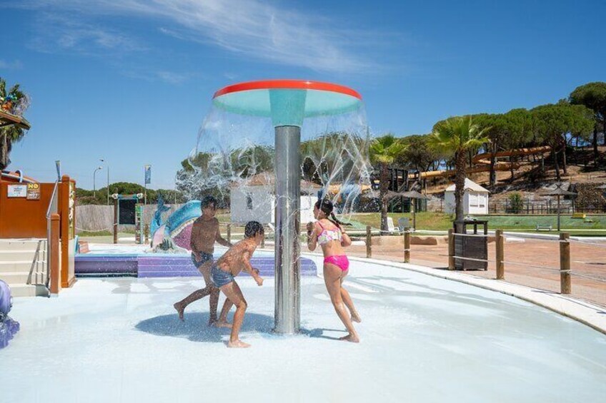 A water play area with children playing, surrounded by palm trees and a clear sky. 3