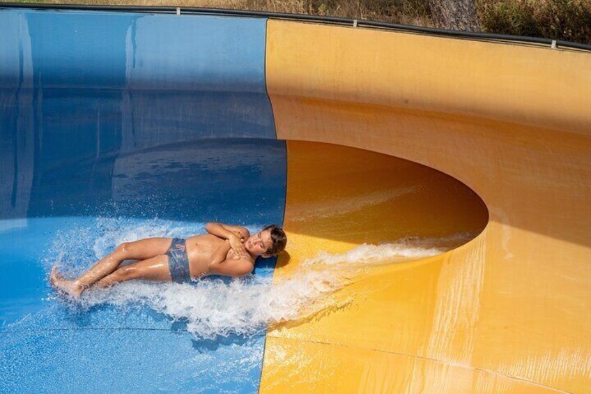 A person lying on a water slide with a blue and yellow section. 2