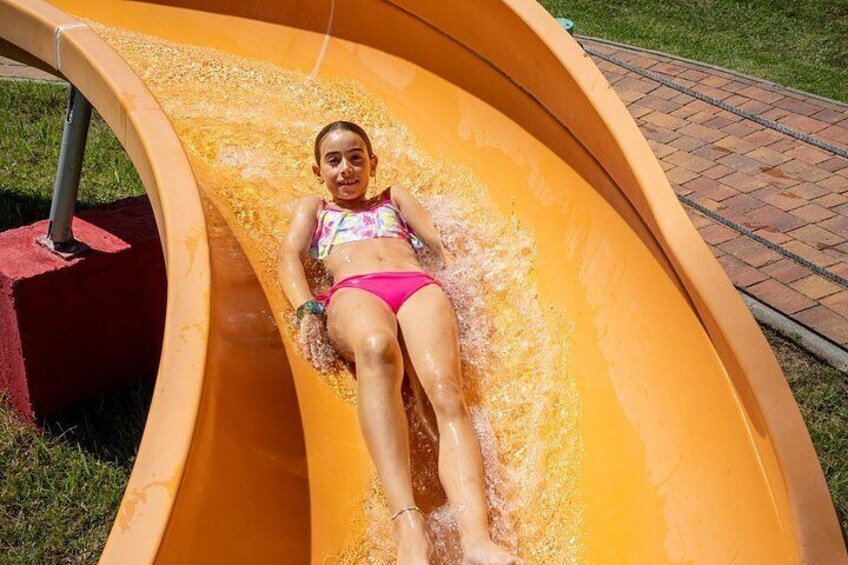 A person lying on a yellow slide in a park. 4