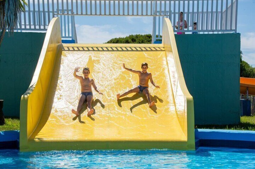 A water slide with two children sliding down into a pool. 1