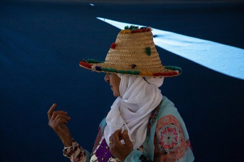 A person wearing a straw hat and a patterned garment, standing on a road with white lines. 3
