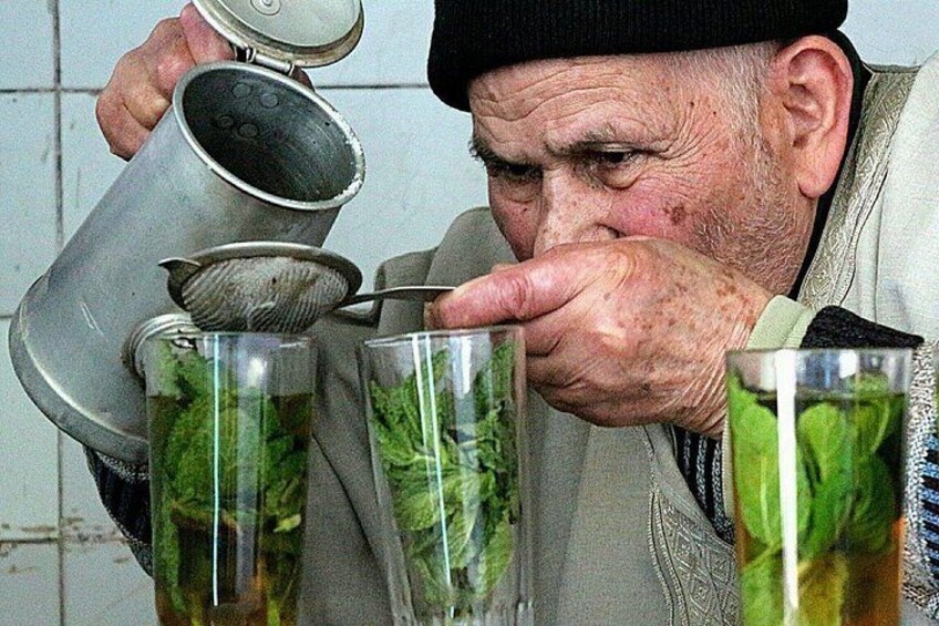 A person pouring liquid from a metal container into a glass. 5