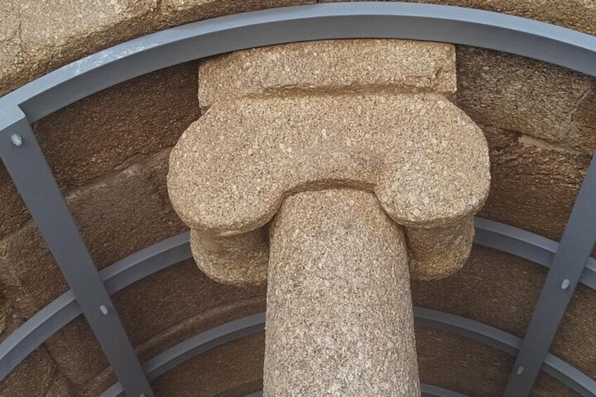 A stone hammer with a cross-shaped head and a cylindrical shaft, mounted on a circular metal frame. 2