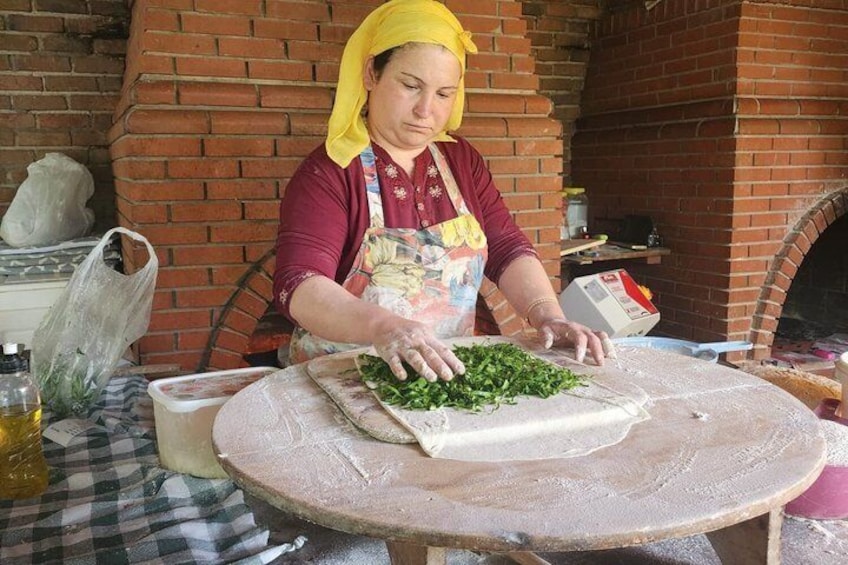 A person preparing food with a large cutting board and a rolling pin on a table. 1