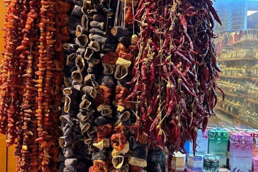Dried chilies and shoes hanging for sale in a market. 3