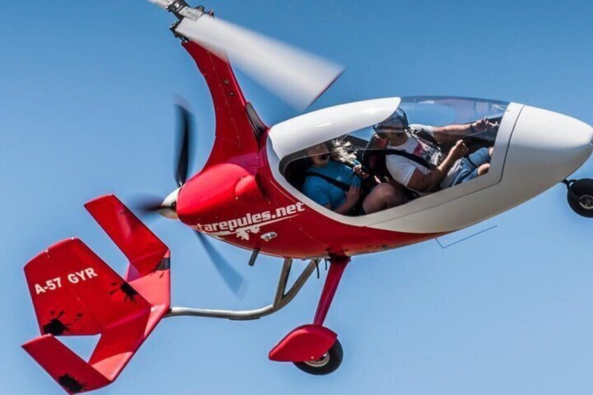 A red and white aircraft with 'A57 GYR' on its tail, flying in clear blue skies. 1
