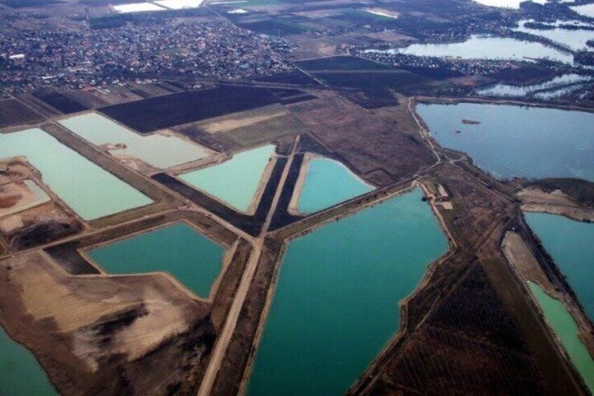 An aerial view of a mining area with multiple ponds and a town in the background. 4