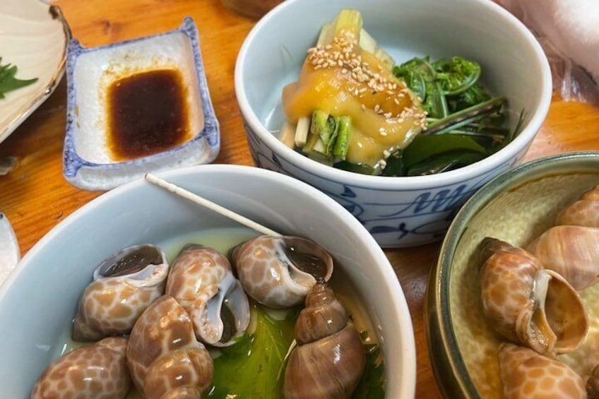 Bowls of food, including snails and a dish with greens and sesame seeds. 4