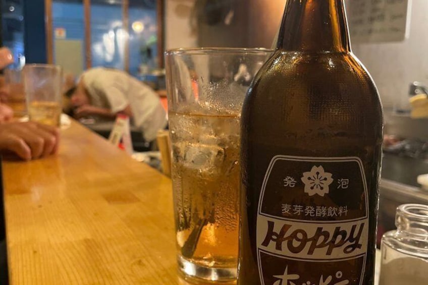 A bottle of Hoppy beer and a glass on a wooden table in a restaurant. 1