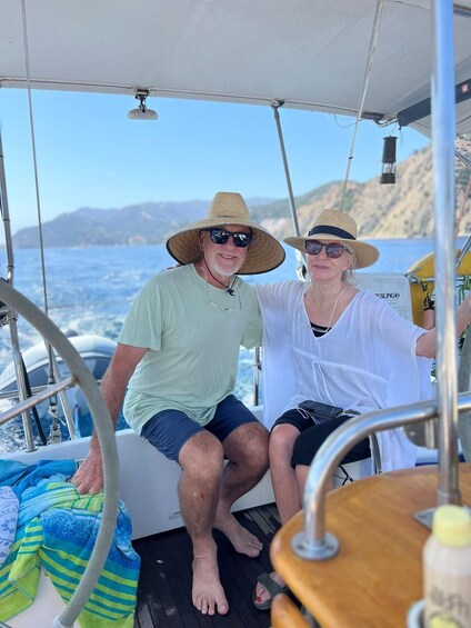 Two people on a boat with a view of the sea and distant hills. 5