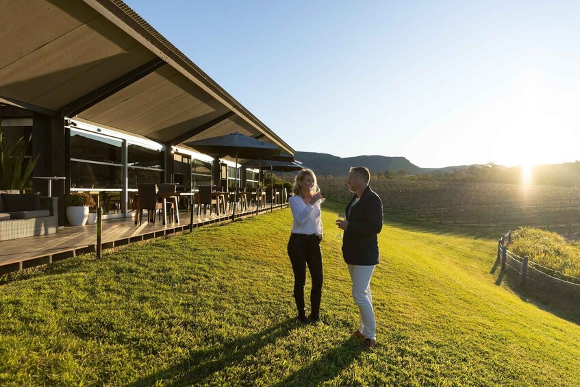 A couple standing on a grassy area with a building in the background. 2