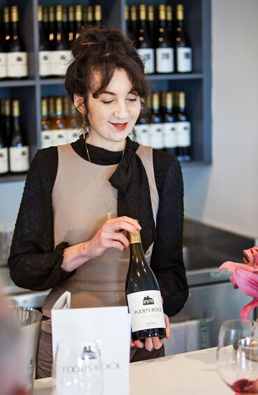 A person holding a bottle of wine with a label that reads 'POOL'S ROCK.' 3