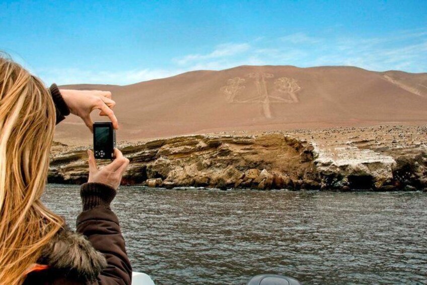 A person taking a photo of a rocky shoreline with mountains in the background. 5