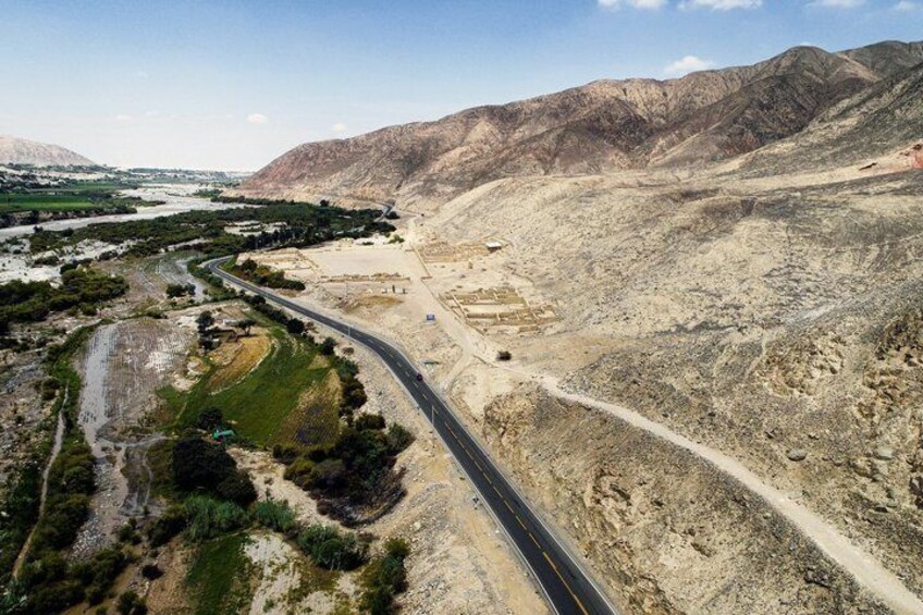 A winding road through a desert landscape with mountains in the background. 1
