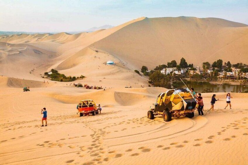 A desert landscape with sand dunes, a dune buggy, and a group of people. 5