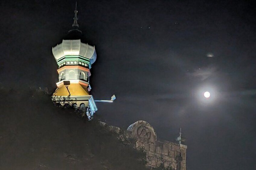 A brightly lit pagoda with a moon in the background. 2