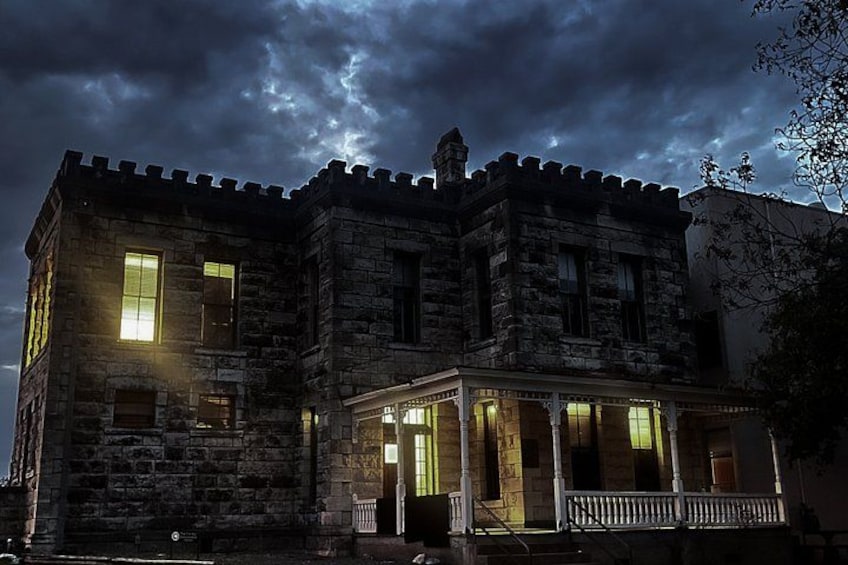 A stone building with a balcony and lit windows at night. 4