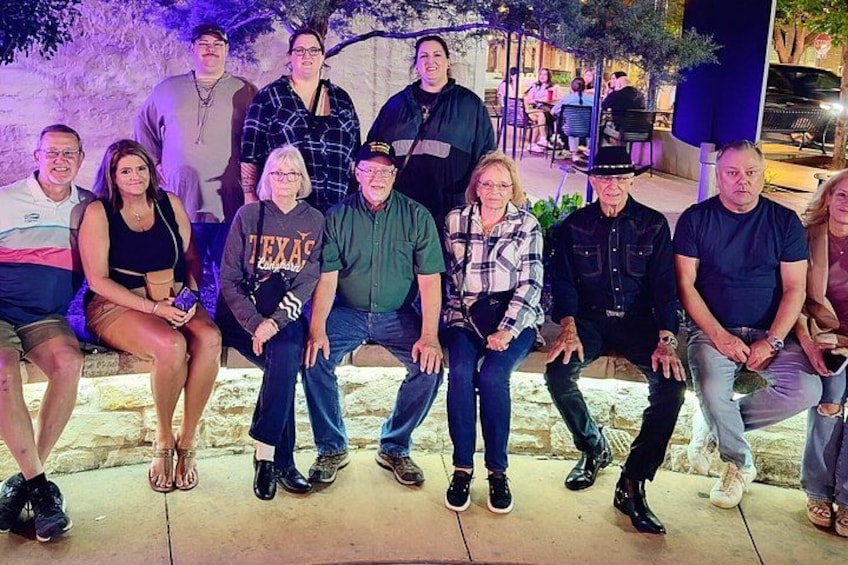 A group of people seated on a stone bench outdoors at night. 2