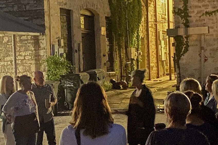 A group of people standing in front of a building with stone walls and a door. 2