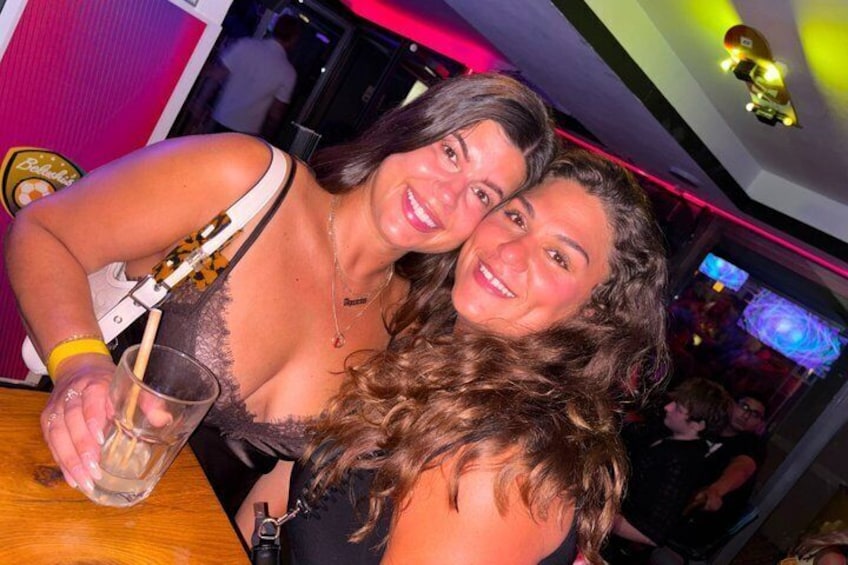 Two people at a bar with a neon sign in the background. 2