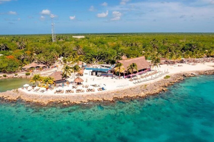 A tropical beach resort with a white sandy shore, clear turquoise waters, and lush greenery. 3
