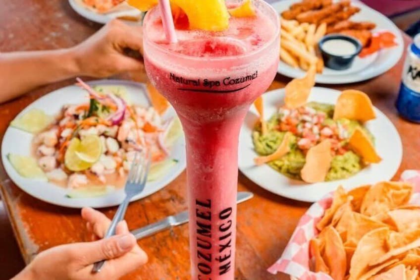 A beverage with a straw and a slice of fruit, a plate of nachos, and a taco dish. 2