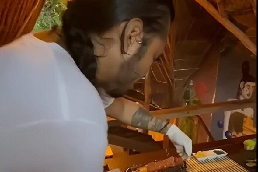 A person preparing food outdoors, possibly grilling, with a grill and some food items visible. 4