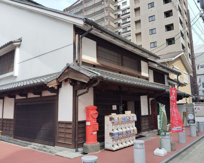 A traditional Japanese building with a tiled roof, wooden beams, and a red mailbox. 4