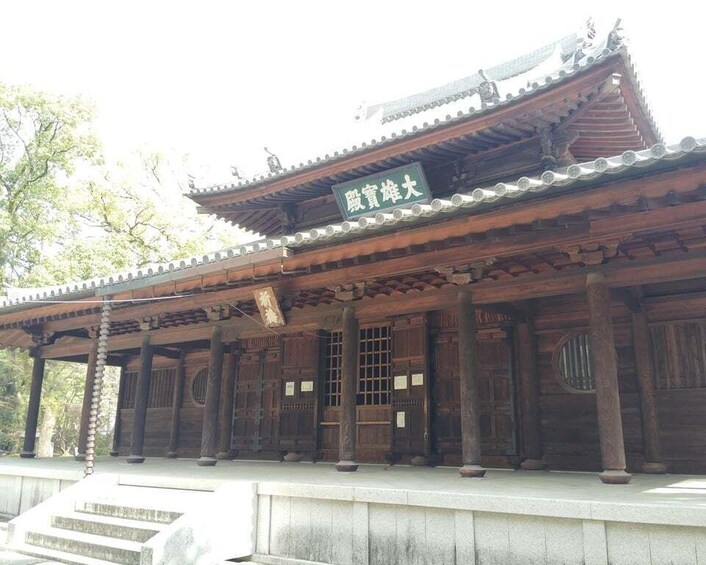 A traditional wooden building with a tiled roof and a sign in a foreign script. 5