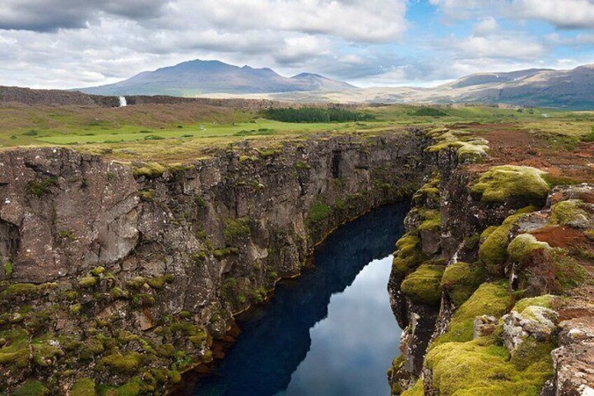 A gorge with a river, rocky cliffs, and distant mountains. 4