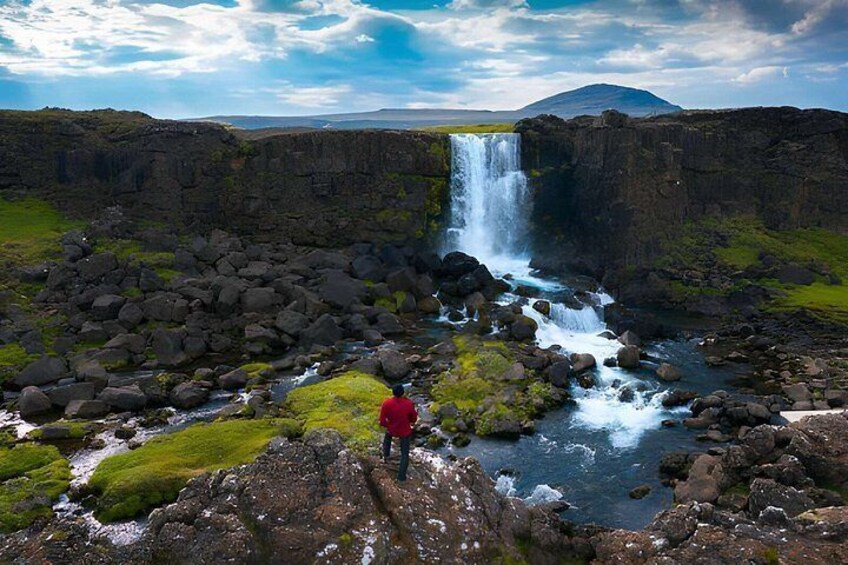 A waterfall, rocky terrain, and a person in a red jacket. 4