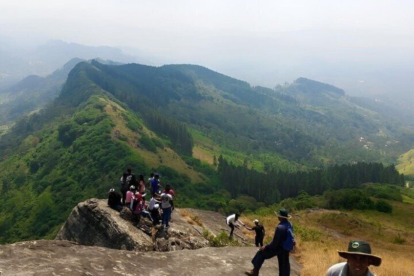 A group of people on a mountain ridge with lush green valleys below. 5