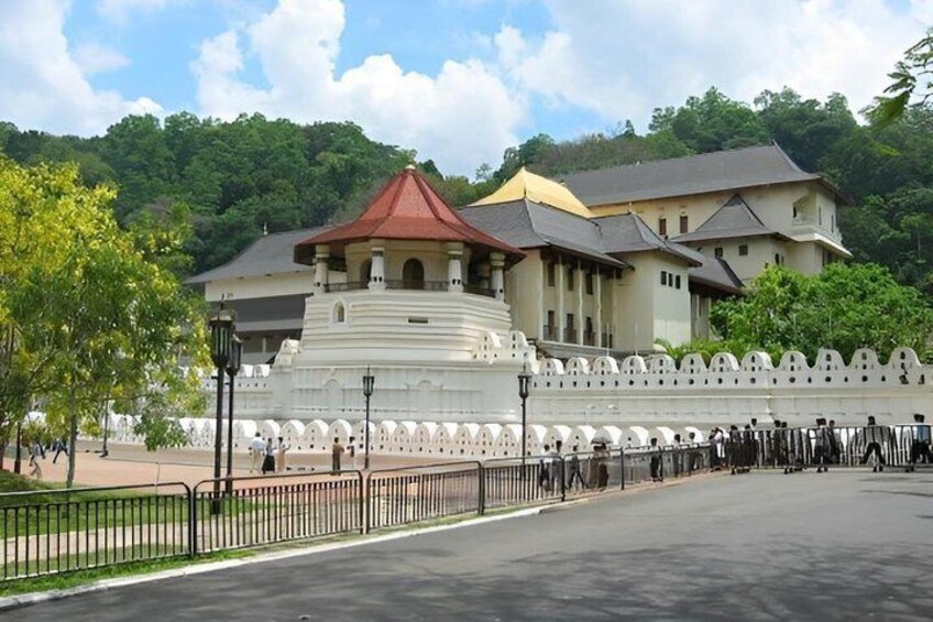 A historical building with a red roof, surrounded by a white wall and a fence. 2