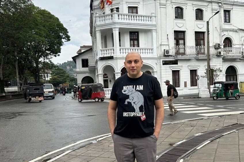 A man standing on a sidewalk with a white building in the background. 4