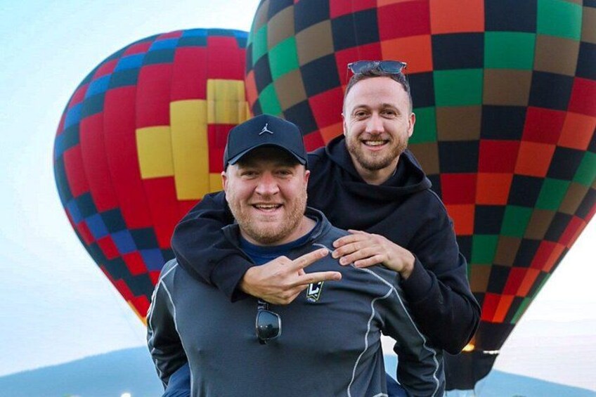 Two people standing in front of a colorful hot air balloon. 4