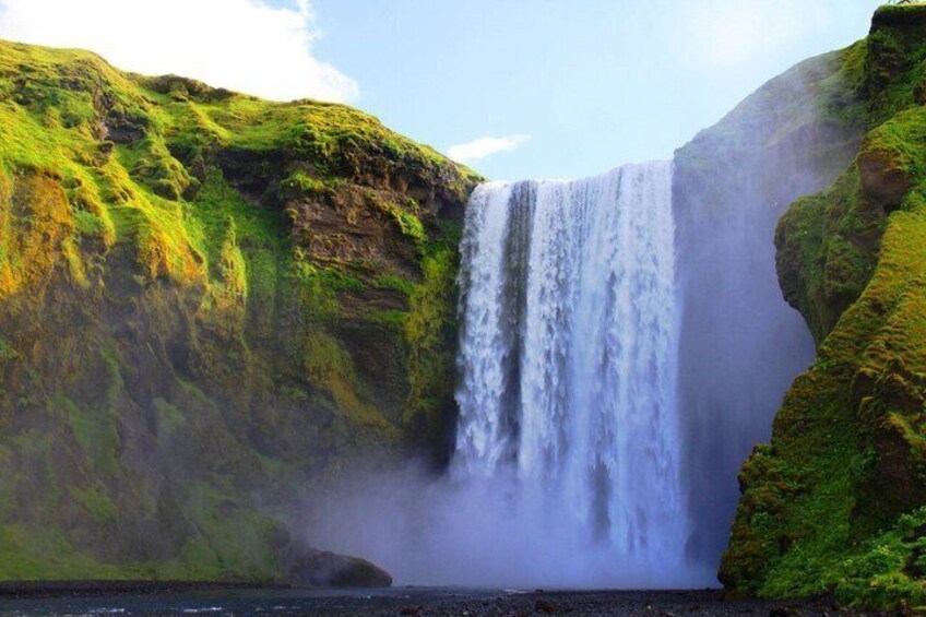 A waterfall cascading down a cliff surrounded by lush greenery. 1