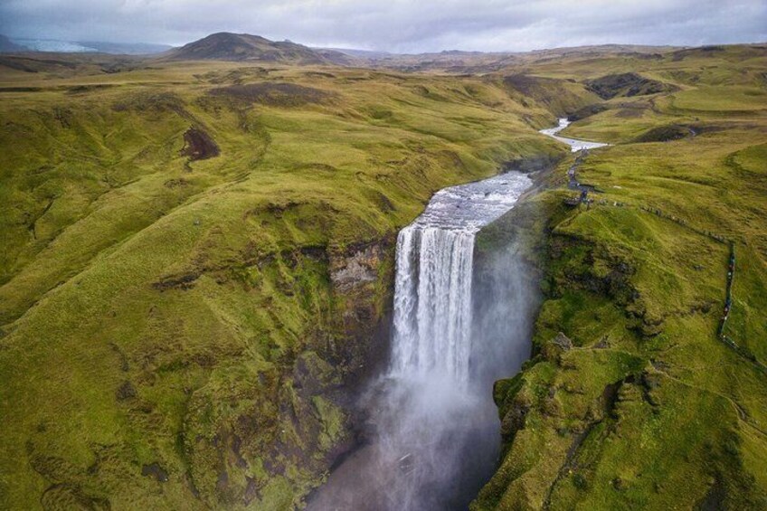 A waterfall in a green valley with a river flowing through it. 5